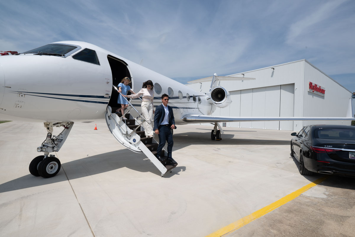 Luxury jet passengers deplaning from a Gulfstream aircraft on a private Texas ramp.