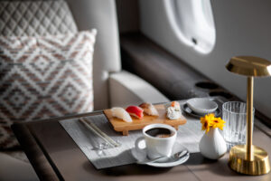 Elegant jet cabin dining setup with sushi, coffee, and flowers, photographed during international private aviation shoot in east asia