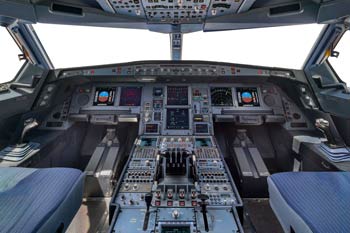 Panoramic interior view of an Airbus flight deck with illuminated overhead panel and avionics displays, photographed by Denver aircraft photographer Dave Koch