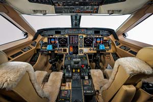 Business jet cockpit photographed by AeroMedia inside a private hangar at Toulouse–Blagnac Airport, featuring modern avionics, dual pilot seats, and flight controls.