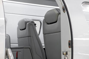 Private jet entryway in the Caribbean showing two modern grey leather passenger seats viewed from the open cabin door.