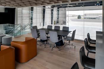 Modern FBO lounge at Nashville International Airport with conference seating, lounge chairs, and large windows overlooking the private jet ramp Aircraft Photographer in Nashville