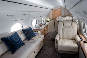 Gulfstream G550 cabin with cream leather seating and light wood finishes photographed at San Jose International Airport