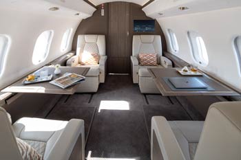Luxury private jet cabin with beige leather seats, workstation tables, and natural light photographed in Chicago, Illinois