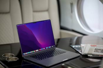 Private jet cabin workspace with polished wood table and window light, photographed at Macau International Airport.