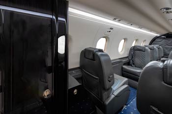 Dark leather private jet seating with soft window light at Macau International Airport.
