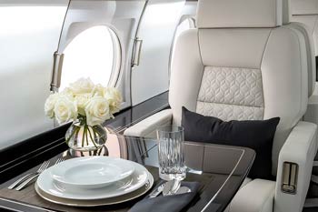 Elegant private jet dining setup with white roses, stacked plates, and glassware inside a luxury cabin at Nashville’s BNA airport