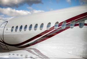Private jet fuselage detail showing oval windows and cheatline reflection, photographed by AeroMedia on the ramp at Nice Côte d’Azur Airport, France.