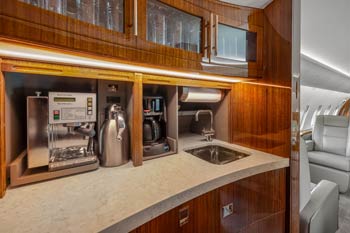 Luxury private jet galley with Nespresso machine, sink, and high-gloss wood cabinetry photographed by aviation photographer Dave Koch at Sydney Kingsford Smith Airport