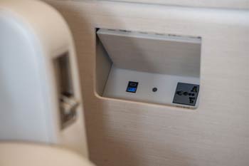 Private jet USB-A and USB-C panel set into beige upholstery, photographed at Macau International Airport.