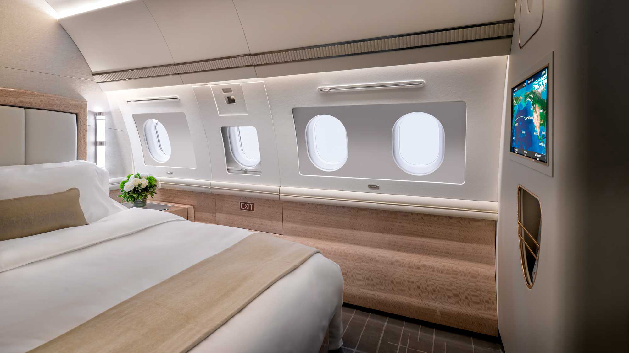 ACJ319 VVIP bedroom suite photographed in Scottsdale, with a centrally positioned queen bed, ambient lighting, gloss cabinetry, and refined neutral decor in a private jet stateroom configuration.