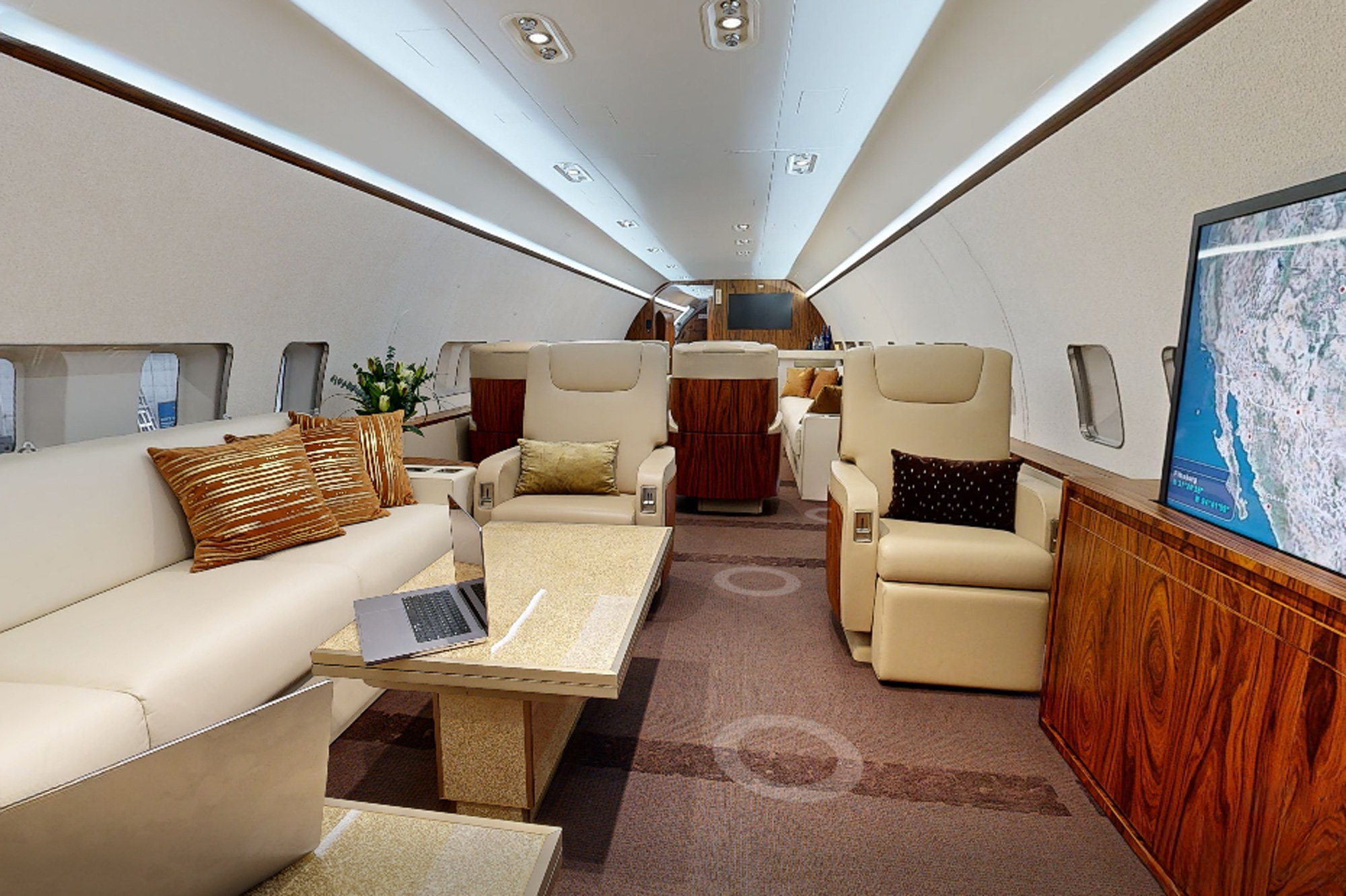 rivate jet lounge photographed in Oklahoma City showing cream seating, flight display, and a staged laptop workspace by Dave Koch.