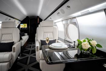 Luxury private jet interior with white leather seating, dining table setup, and floral arrangement photographed at Wichita Eisenhower National Airport