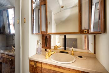 Private jet lavatory with wood cabinetry, gold fixtures, and vanity mirror photographed at Wichita Eisenhower National Airport