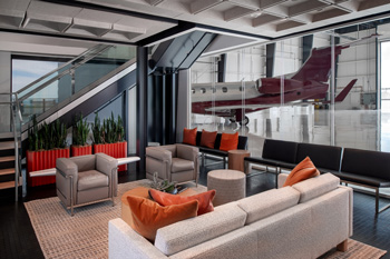Luxury private hangar lounge at Salt Lake City Airport with contemporary seating, plants, and a business jet positioned just outside the open hangar.
