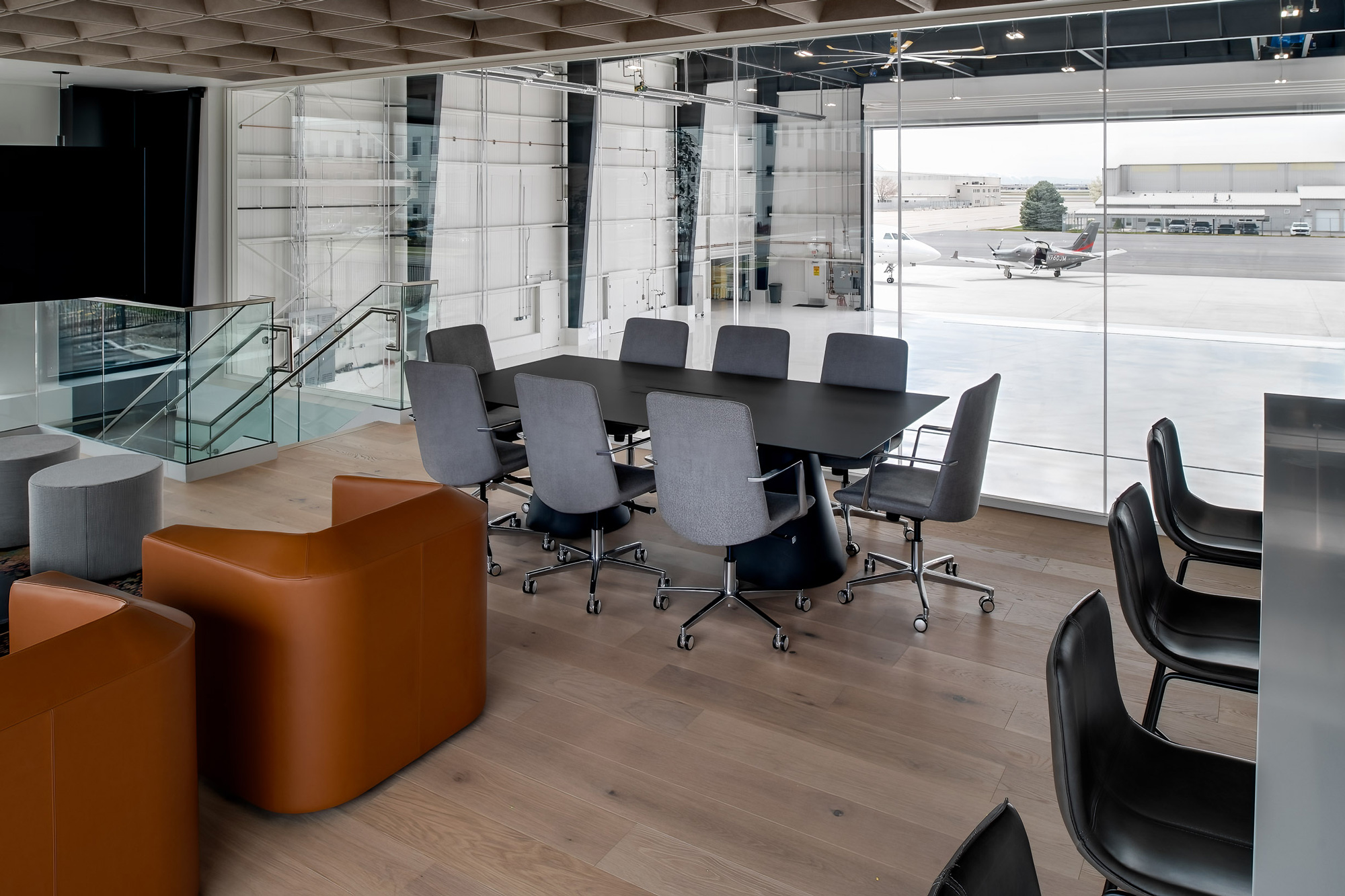 Glass-walled conference room above a Teterboro hangar with a view of the ramp and a light aircraft outside.
