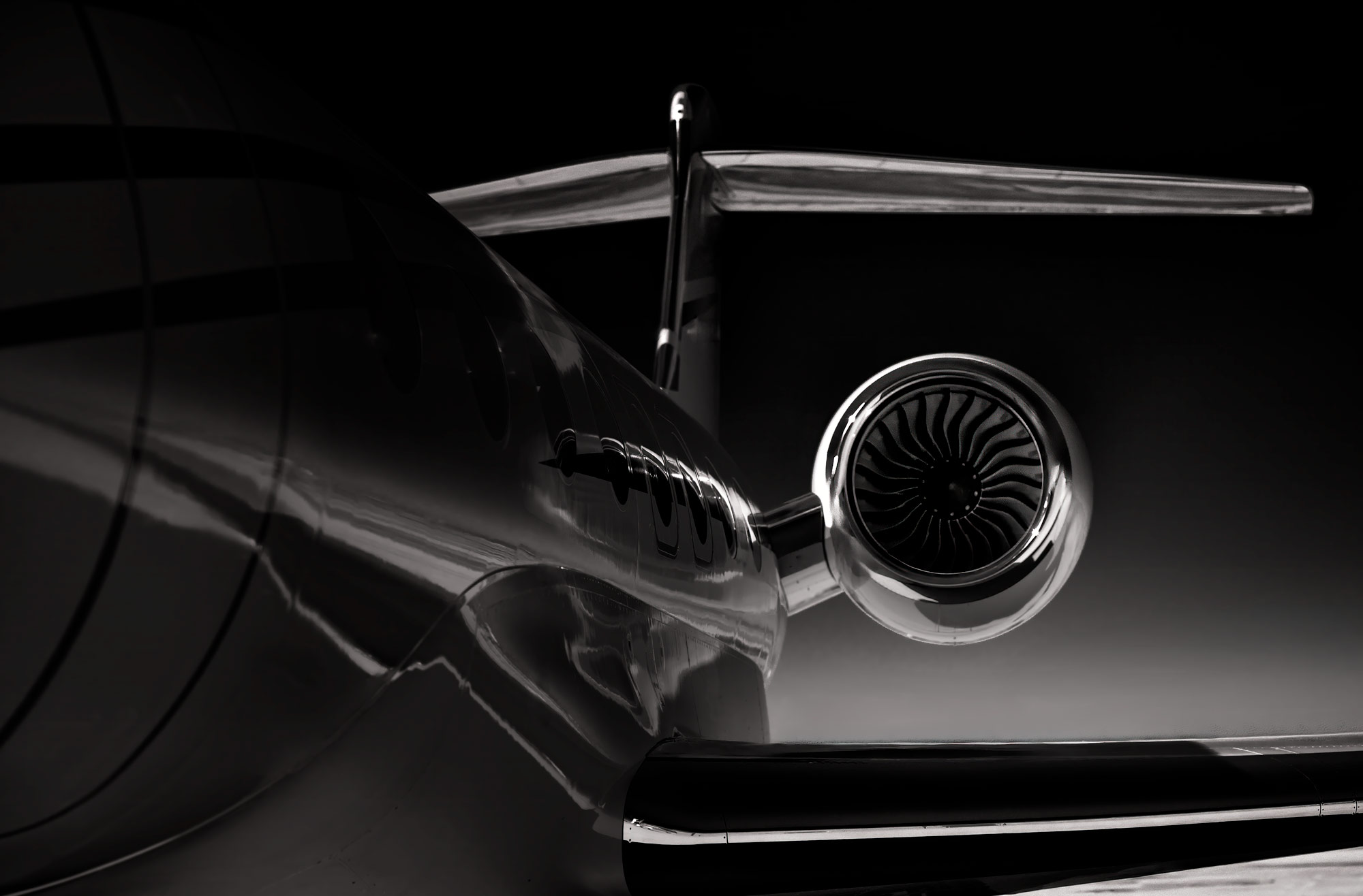 Moody black and white image of a business jet from the rear side, emphasizing engine symmetry and sleek fuselage reflections against a dark gradient background.