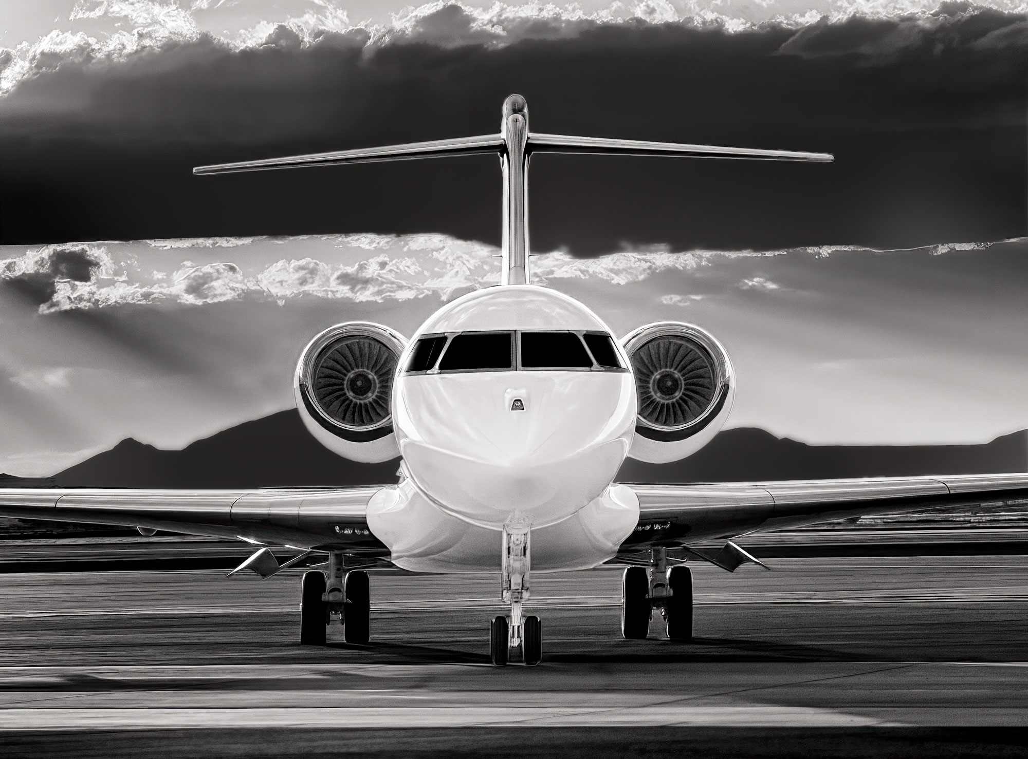 A head-on portrait of a long-range business jet, rendered in black and white for maximum impact.